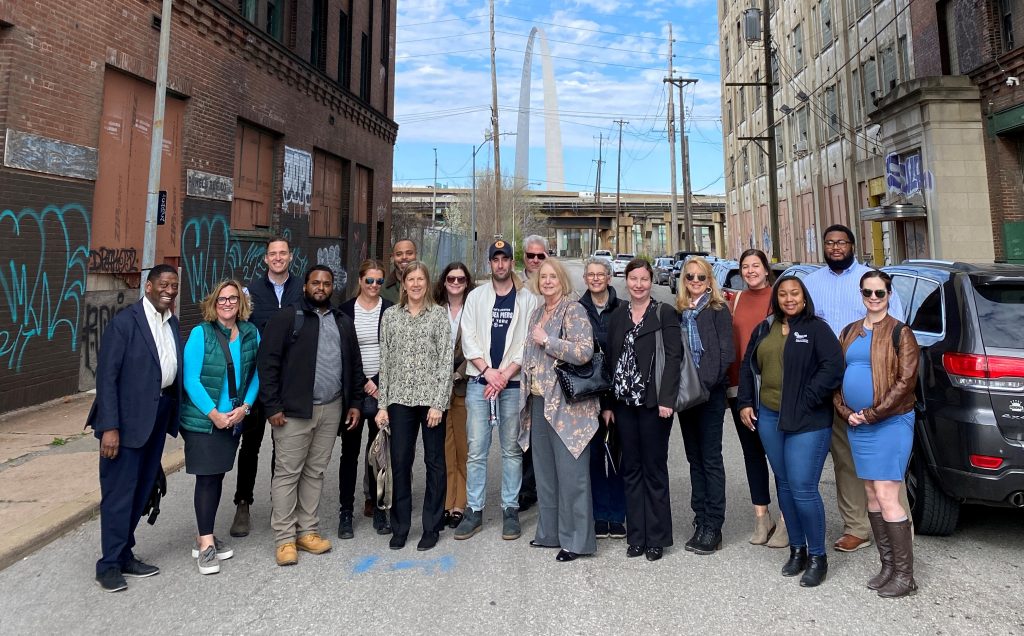 A group of people stand in an alleyway in front of the arch