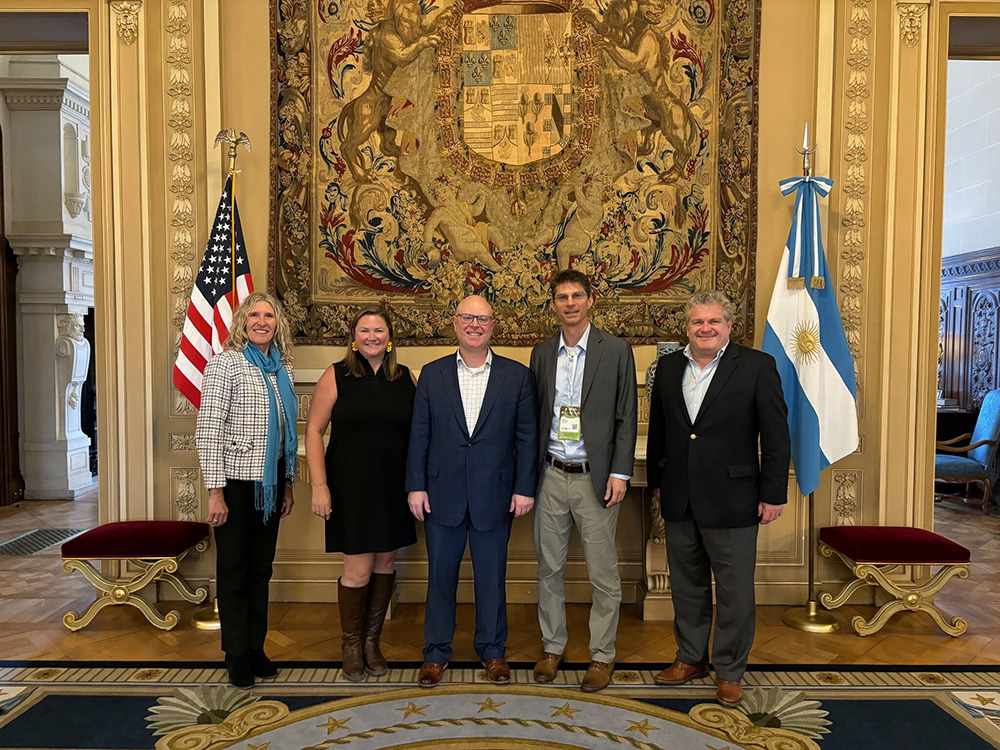 A group of people stand in front of the American and Argentinan flag