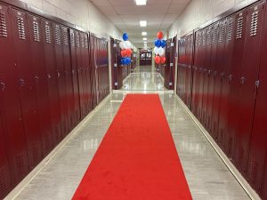 A long hallway decorated with a red carpet and balloons