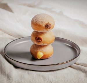 3 Venezuelan donuts are stacked on a plate with fillings spilling out 