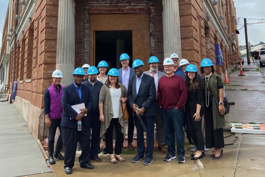 A group of people stand outside of a building wearing blue hard hats