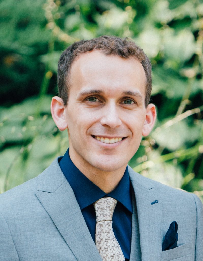 man in a suit outdoors smiling