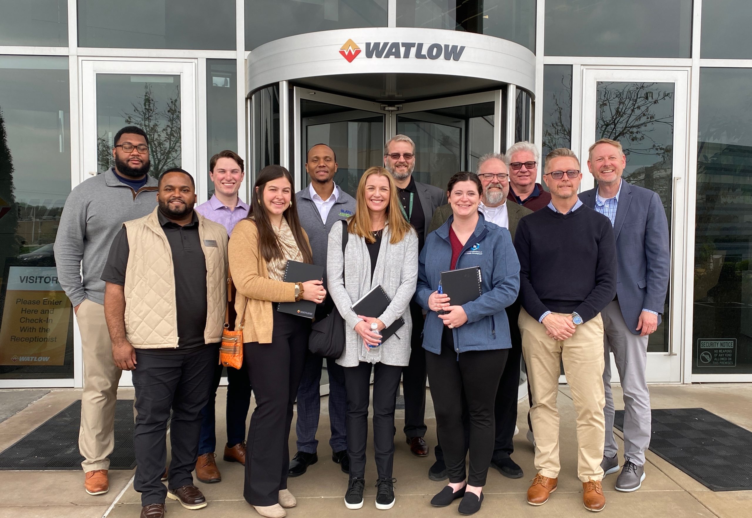 Watlow BRE A group of people stand in front of a building. The name above the door says Watlow