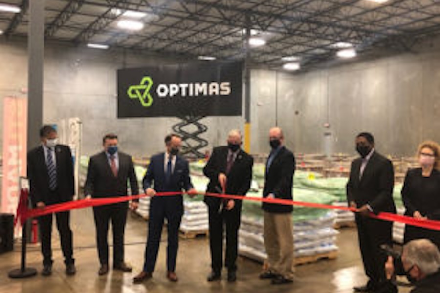 Image of a ribbon cutting with a sign that says Optimas