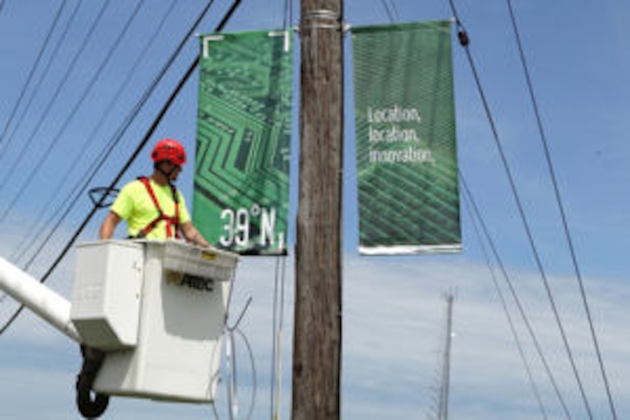Image of a man installing a banner on a telephone pole