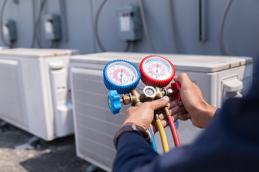 Man holding a pressure gage in front of AC units.
