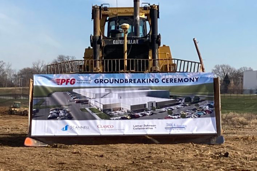 A bulldozer on a grass field. Inside is a banner with the text, "PFG, Groundbreaking Ceremony."