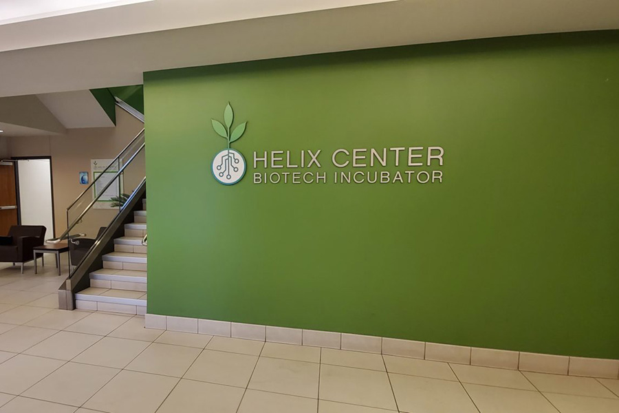 Inside of the Helix Center building, green wall reads, "Helix Center Biotech Incubator"
