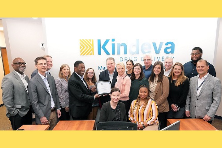 Group of individuals smiling in front of the Kindeva Drug Delivery sign