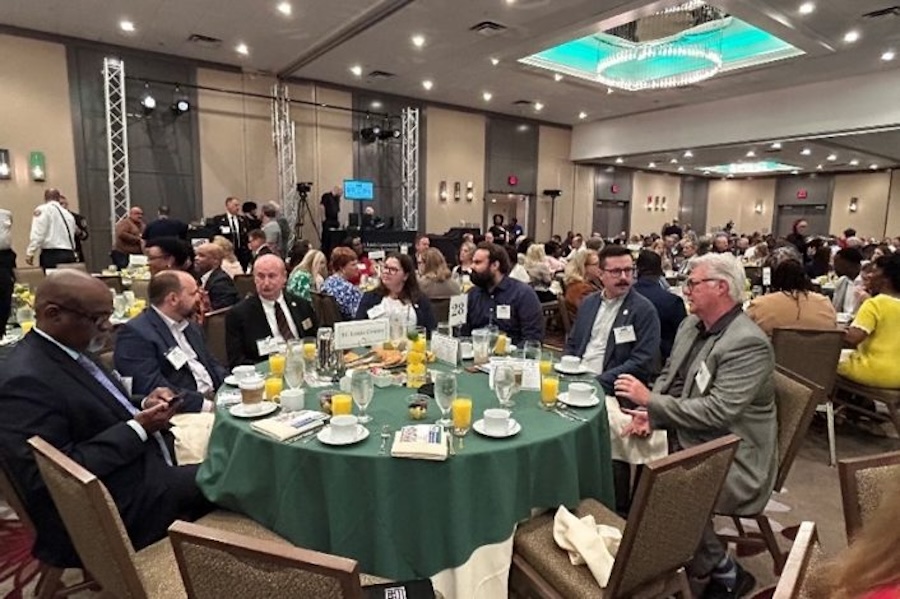 A table of 7 sitting at a round table, having conversations. They are attending the NCI Leadership Breakfast.