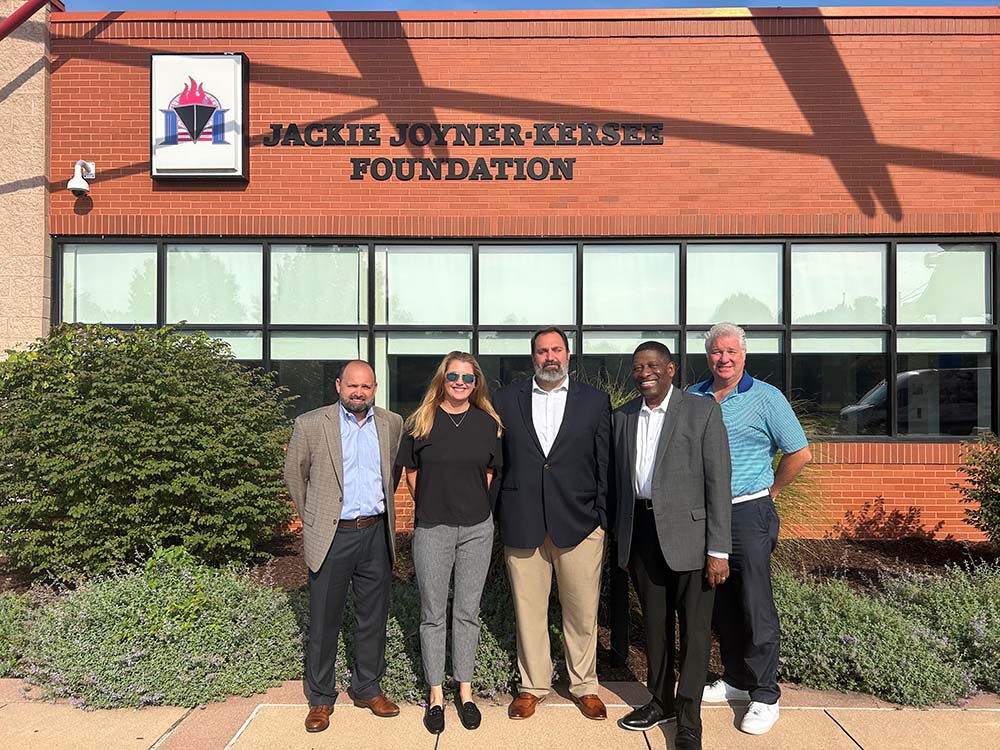 A group of people stand in front of a JJK foundation sign