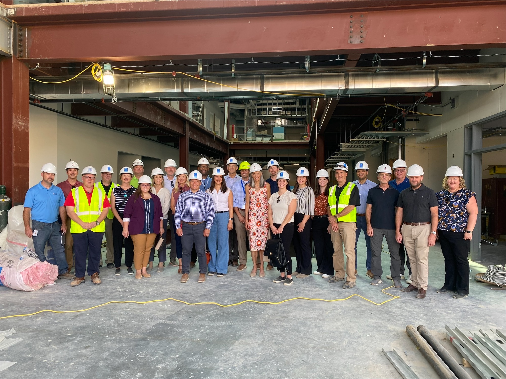 A group of people with hard hats on stand posed for a photo