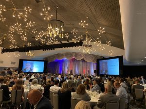 A crowd sits in a highly decorated room