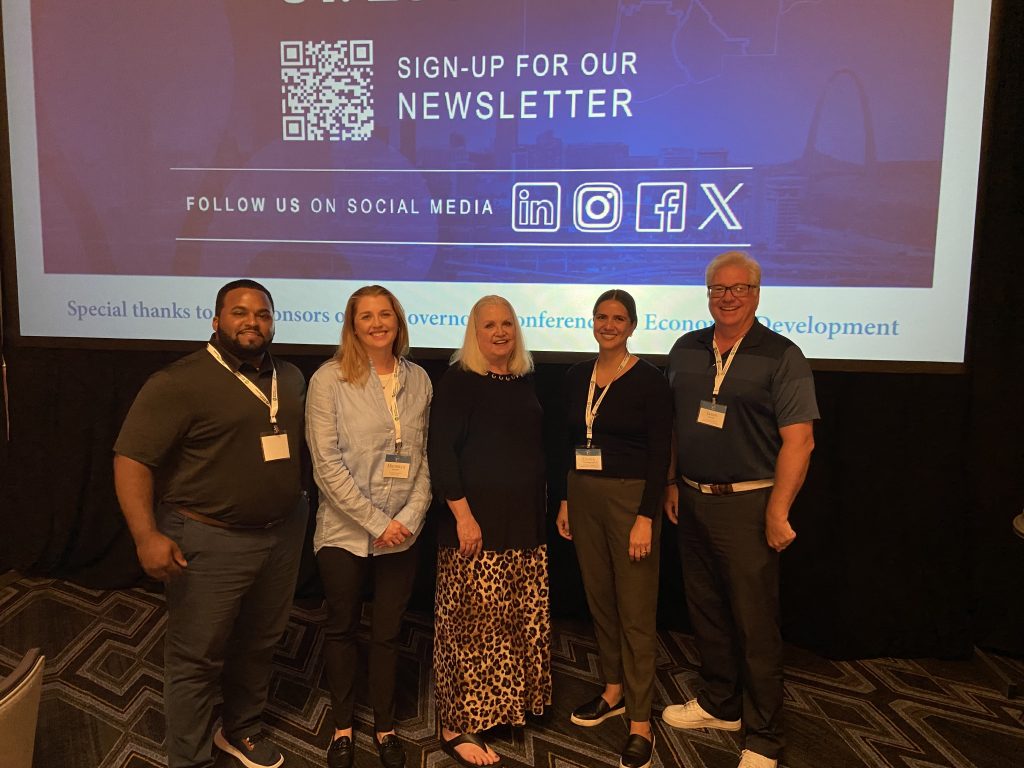 A group of people pose for the camera in front of a slideshow