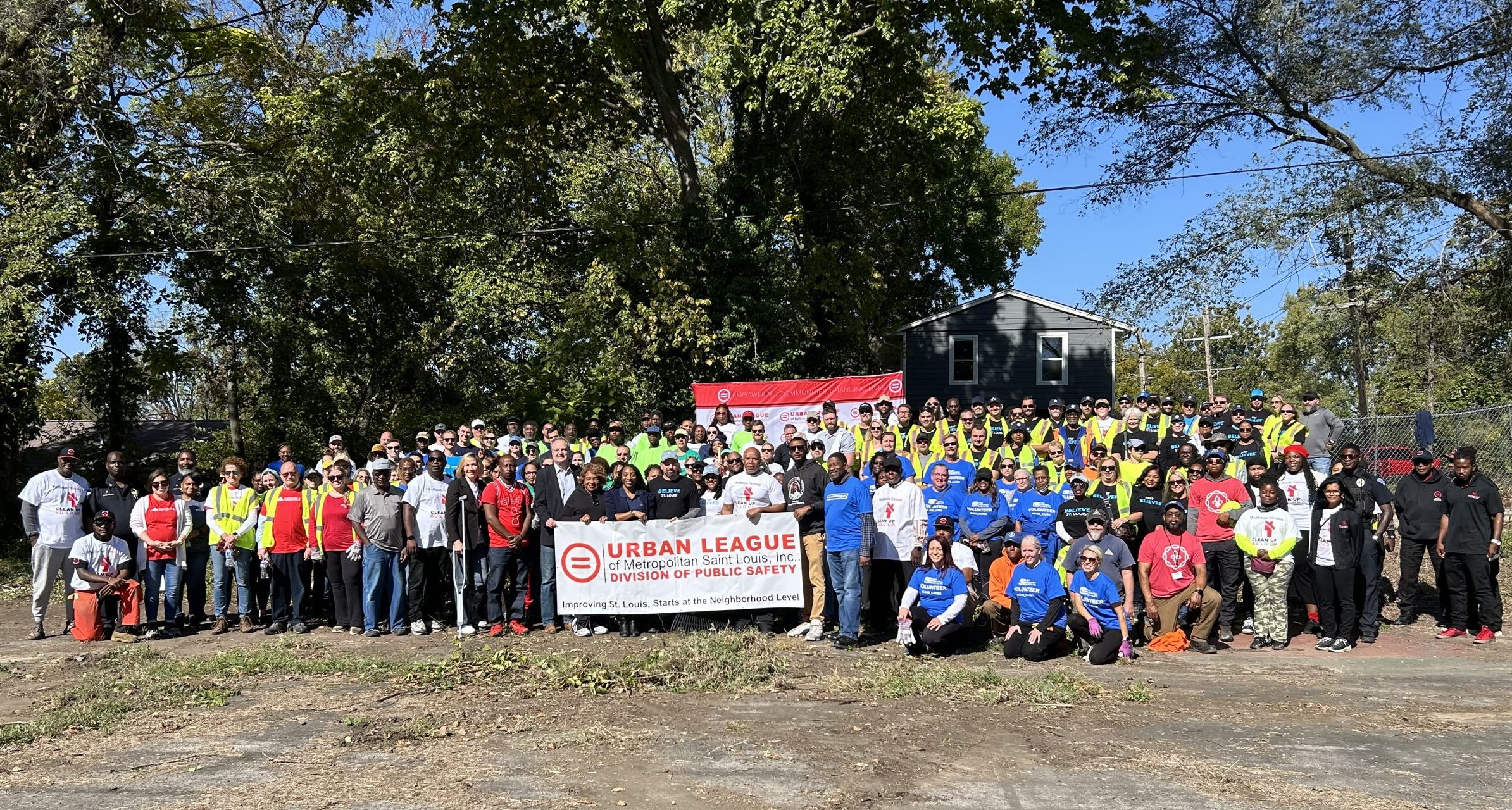 A large crowd stands outside in front of an Urban League sign