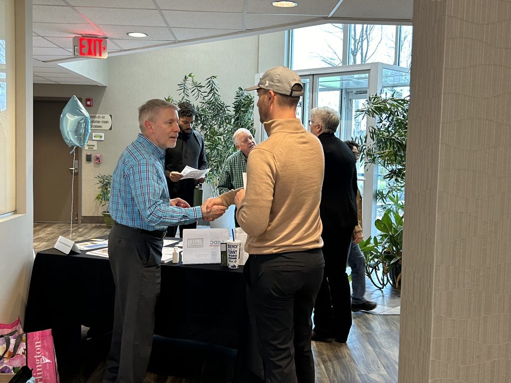 Two men shake hands in front of a table