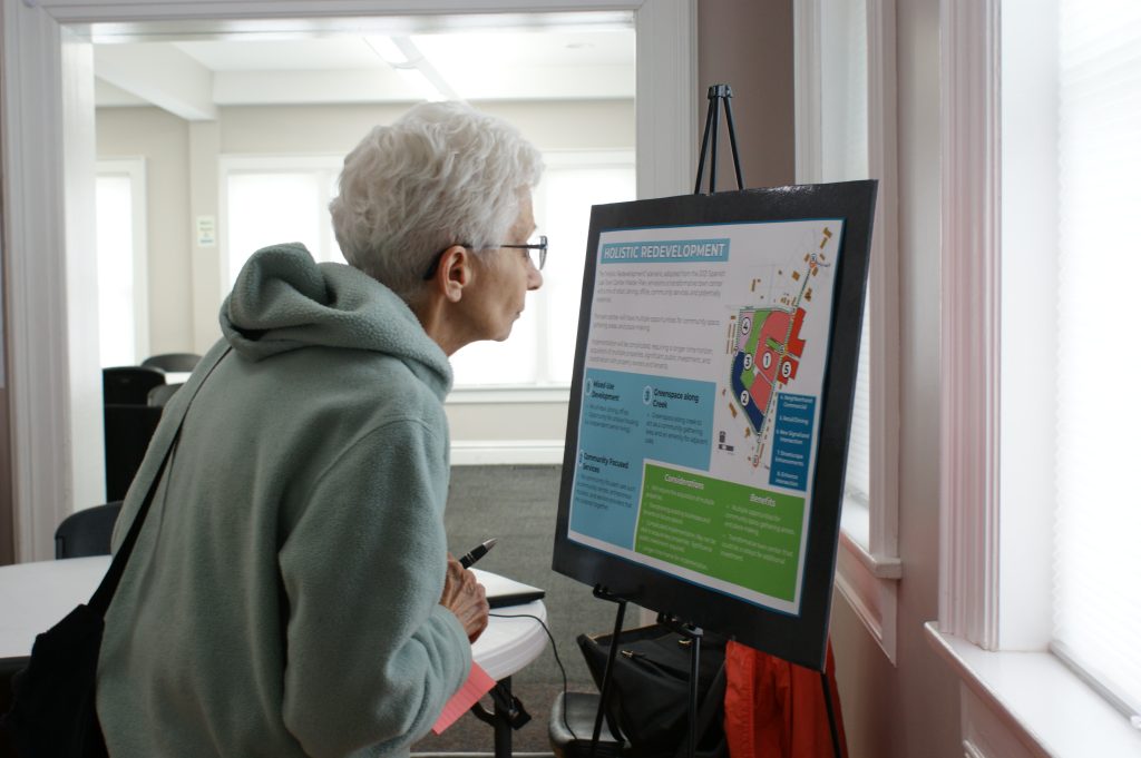 A woman in a hoodie reads a sign
