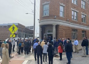 People gather outside a wedge shaped building