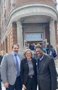 3 people pose for a photo in front of a building