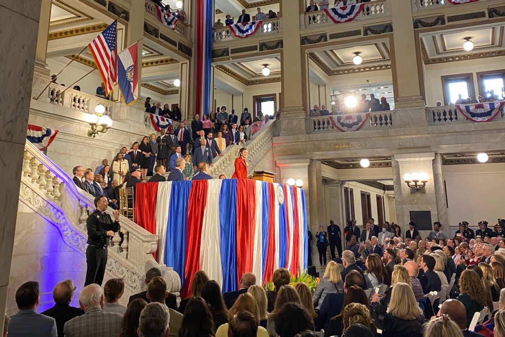 a woman speaks at a podium above a large crowd