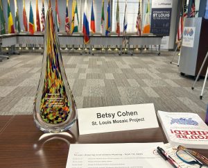 image of a glass award on a table next to a name tag that says Betsy Cohen