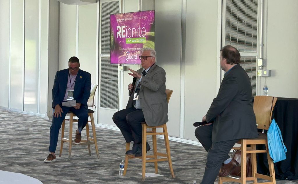 3 men sit in chairs speaking