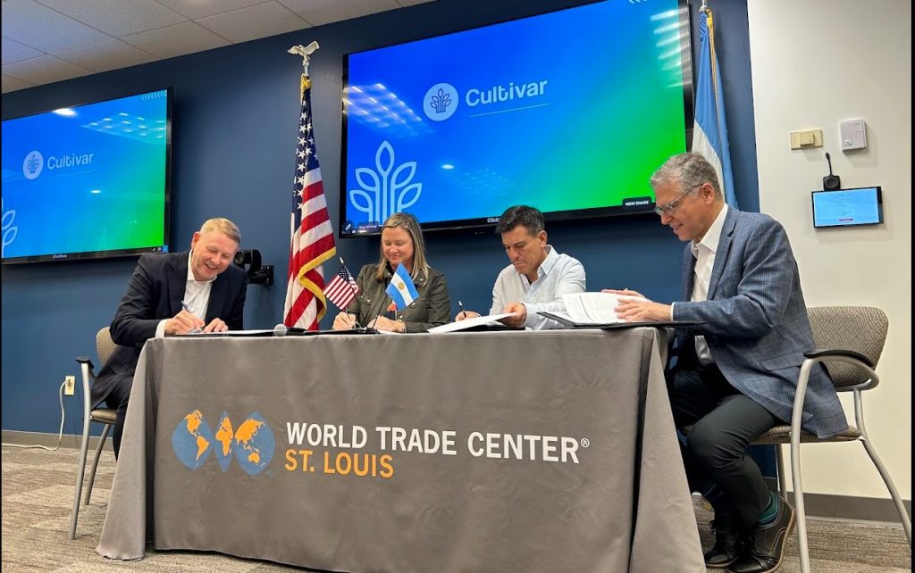 4 people sit at a table inside and sign a document