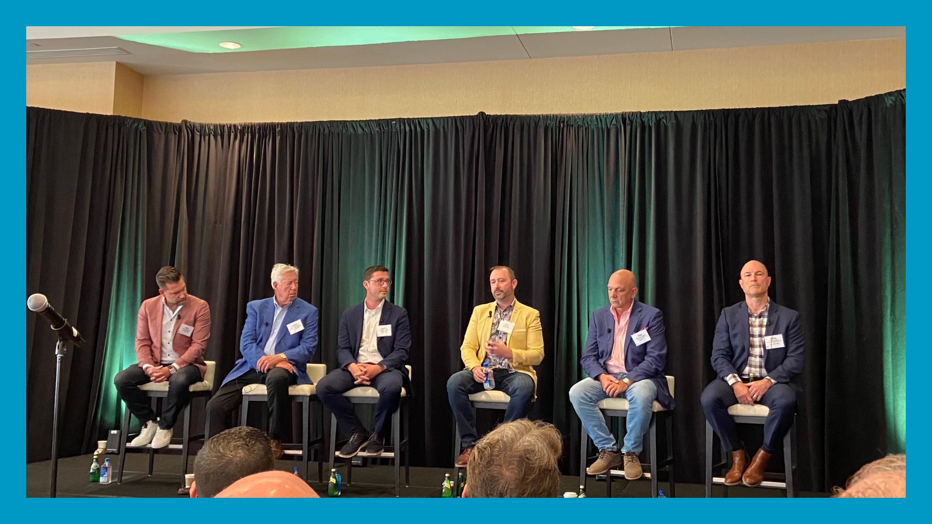 people sitting on stage in line. Surrounded by blue box