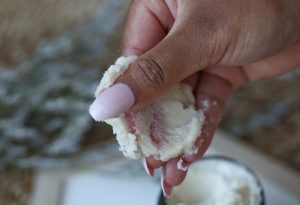 hand spreading body scrub on fingers