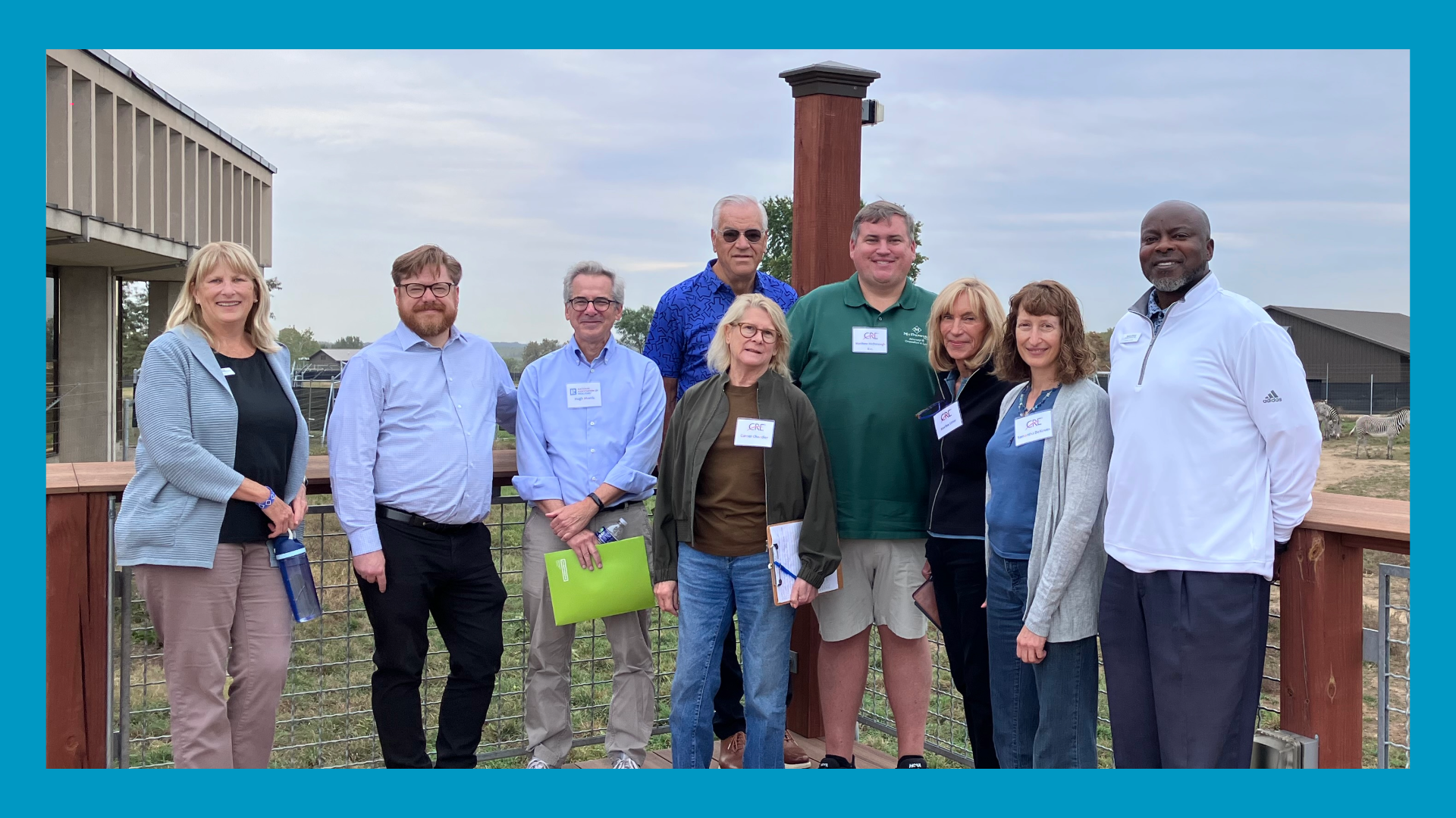 People stand on a deck outside. A blue border surrounds the image