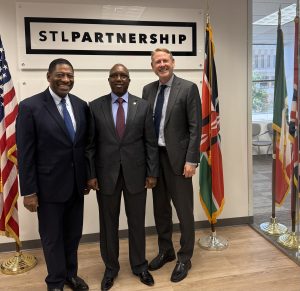 3 men stand between flags