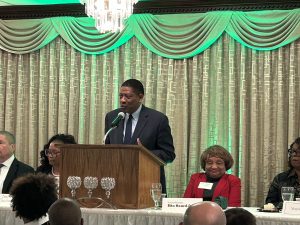 A man stands at a podium with green lighting in the background