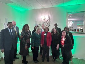 A group of people stand together. The background has green lights