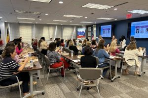 a room of people sits and listens to a panel discussion