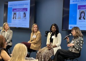 4 women sit in front of a room, one is talking into a microphone