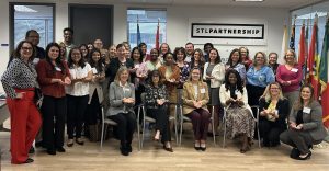 Many people, some standing and some sitting, pose for a picture in a room