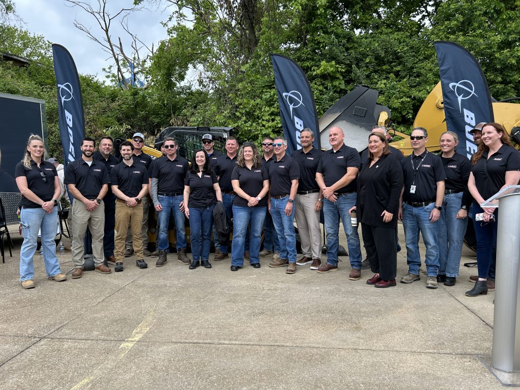a tremendous amount of people wearing black Boeing shirts gather together for a photo outdoors