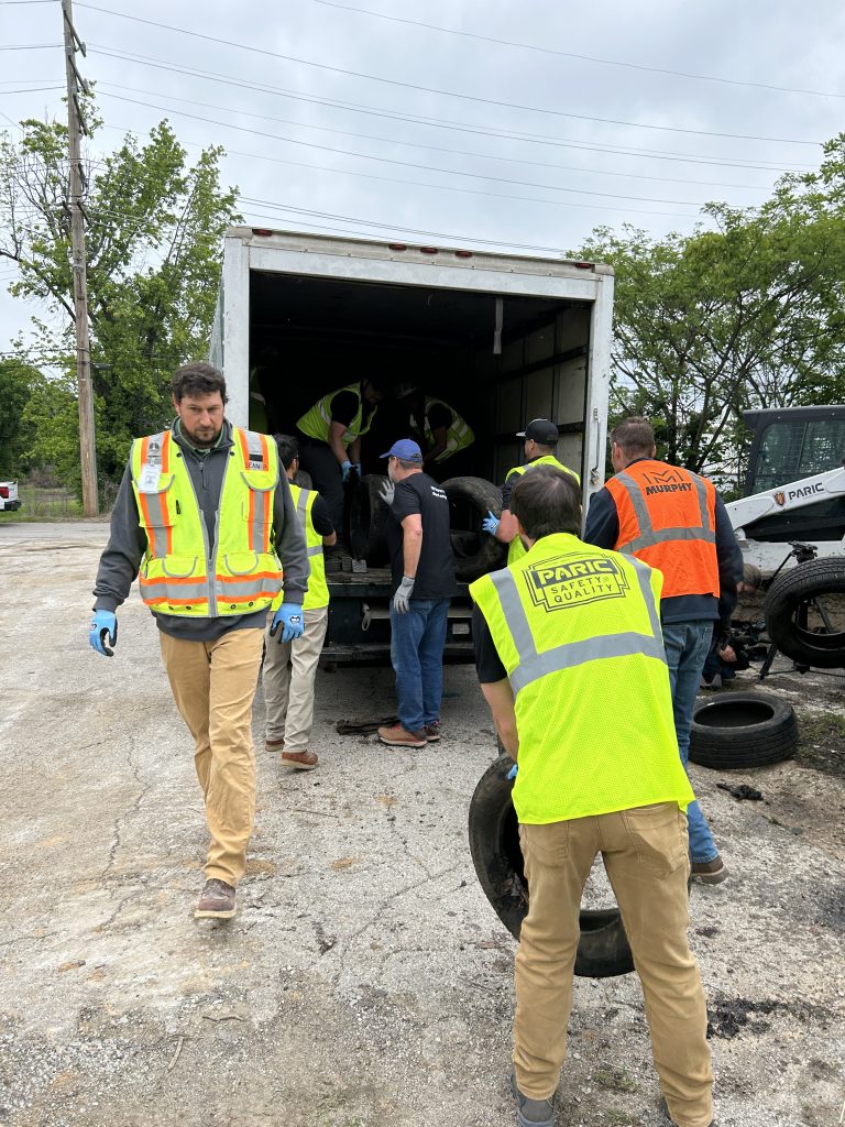 many people in hi-vis vests load up a truck with tires