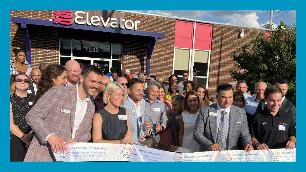 Elevator St. Louis ribbon cutting with large crowd behind. Blue border surrounds image