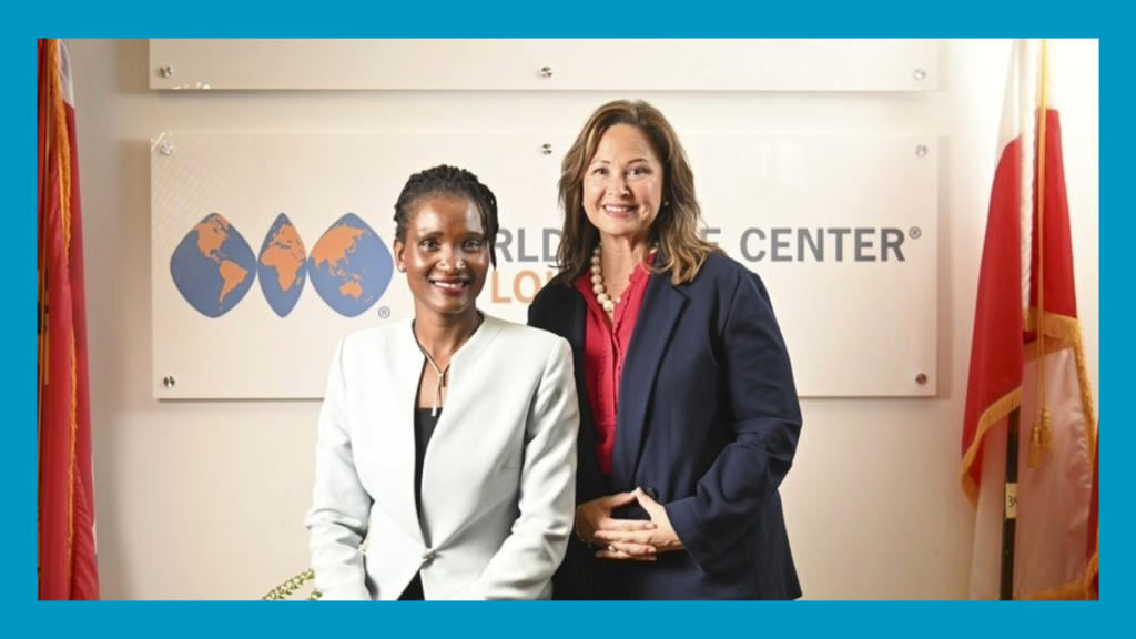 two women pose for the camera. Blue border surrounds image
