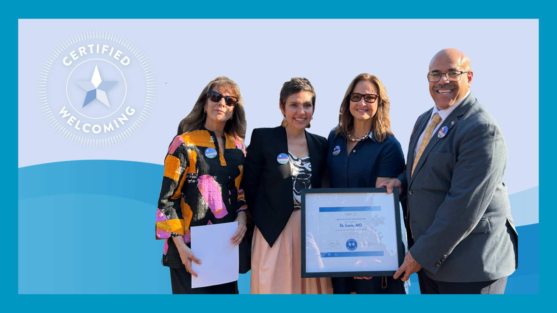 4 people hold the STL welcoming designation plaque. A blue background is behind them with the certified welcoming logo star in the corner.
